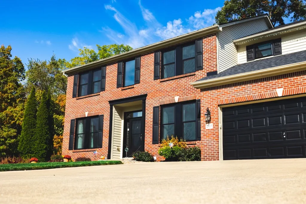 Two-story brick home with black-framed double-hung replacement windows and shutters in Columbus, OH