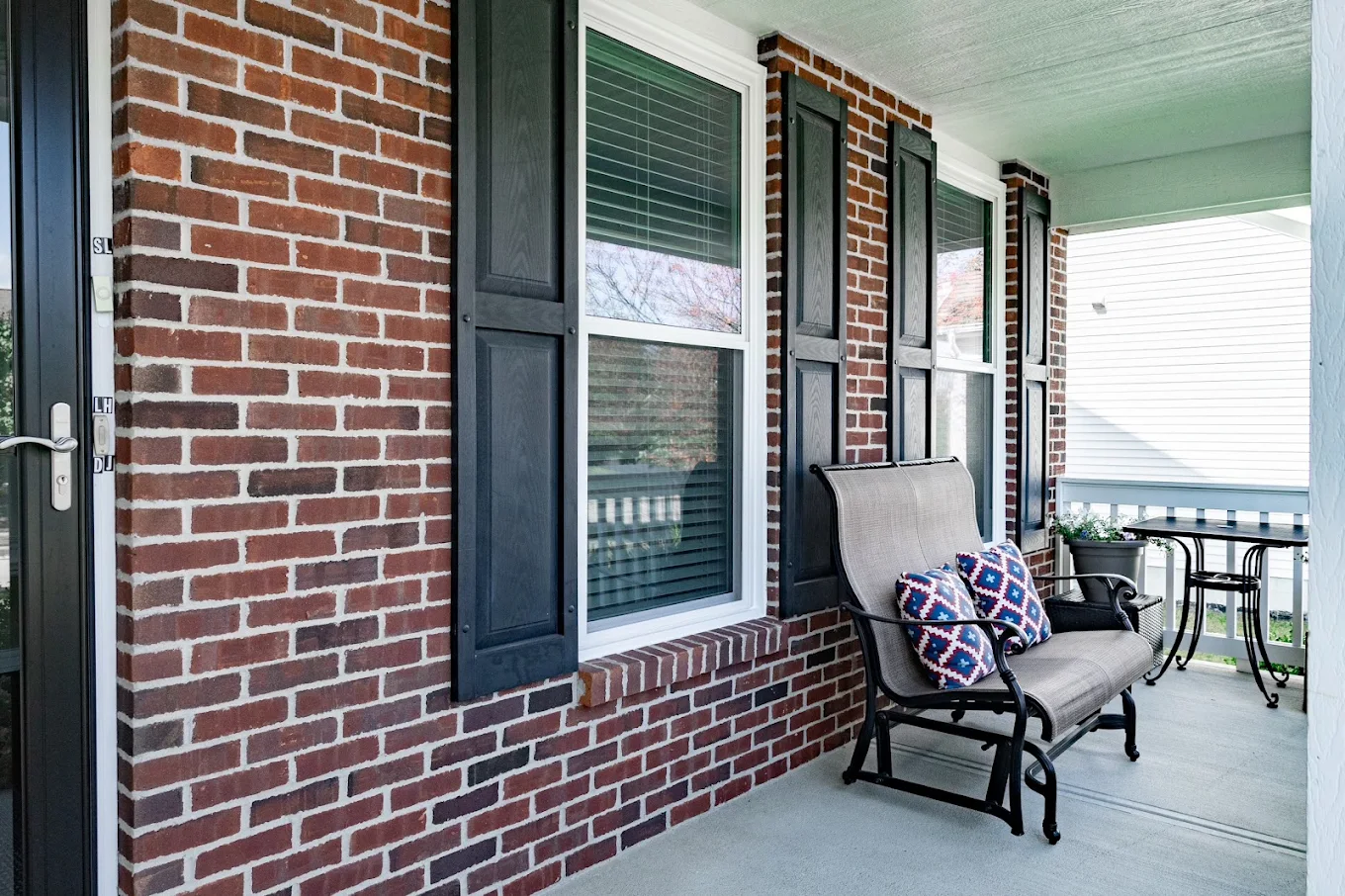 Close-up of durable vinyl replacement windows installed on a brick front porch in Columbus, OH