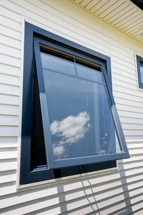 Custom dark-frame awning replacement window pushed open on light siding by Zion Windows in Columbus, OH